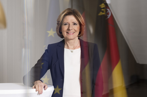 Porträtfoto von Ministerpräsidentin Malu Dreyer mit Europa- und Rheinland-Pfalz-Flagge im Hintergrund.