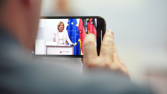 Ein Mitarbeiter der Staatskanzlei nimmt per Smartphone ein Video der Ministerpräsidentin auf.