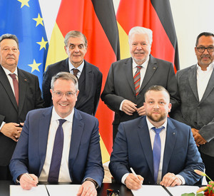 Ministerpräsident Alexander Schweitzer und der Vorsitzende des Landesverbandes Deutscher Sinti und Roma, Christian Kling, unterzeichnen den Staatsvertrag.