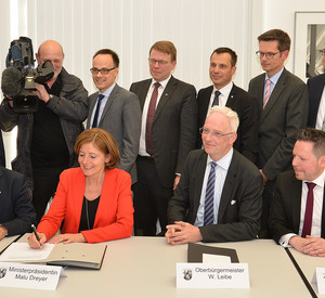 (hintere Reihe, v.l.) Dr. Günther Mattheis, Präsident der Landesärztekammer Rhld.-Pf., Prof. Dr. Ulrich Förstermann (Wissenschaftlicher Vorstand und Dekan Universitätsmedizin Mainz), Dr. Denis Alt, Staatssekretär Wissenschaftsministerium,  Prof. Norbert Pfeiffer, Medizinischer Vorstand Universitätsmedizin Mainz; Dr. Wolfgang Thomas, Ärztlicher Direktor am Klinikum Mutterhaus der Borromäerinnen (sitzend, v. l.) Prof. Winfried Willinek, Ärztlicher Direktor Krankenhaus der Barmherzigen Brüder; Ministerpräsidentin Malu Dreyer,  Trierer Oberbürgermeister Wolfram Leibe; Prof. Dr. med. Winfried A. Willinek, Ärztlicher Direktor Krankenhaus der Barmherzigen Brüder Trier) und weitere Vertreter der Kooperationspartner bei der Unterzeichnung.