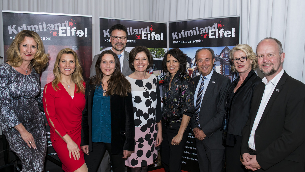 Staatssekretärin Heike Raab, SWR-Moderatorin Patricia Küll, Barbara Philipp / Ermittlerin im Tatort Wiesbaden (stammt aus Wittlich), hinten (groß) Heinz-Peter Thiel / Landrat des Vulkaneifelkreises, Ministerpräsidentin Malu Dreyer, Ulrike Folkerts (dienstälteste Tatort-Kommissarin Lena Odenthal / Ludwigshafen), Tatort-Eifel-Festival-Leiter Heinz-Peter Hoffman, Astrid Schmitt / MdL Vulkaneifel,  Ralf Kramp (Krimiautor und Leiter des Krimihauses Hillesheim) 