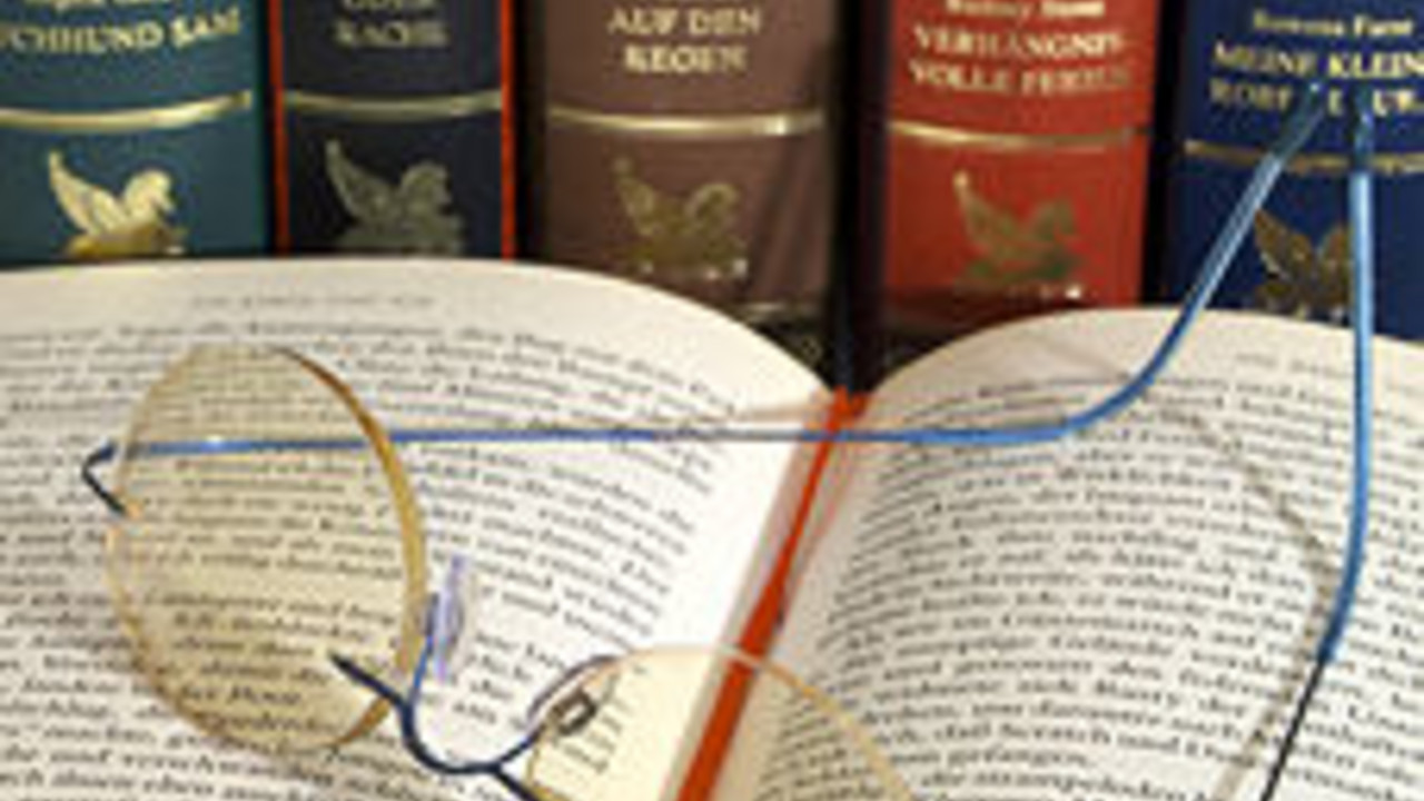 Aufgeschlagenes Buch mit Lesebrille