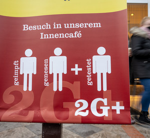 Ein Schild weist auf die 2G Plus Regel in einem Café hin.
