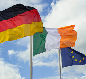 Die Flagge der Bundesrepublik Deutschland, der Republik Irland und die der Europäischen Union vor einem wolkenverhangenen Himmel
