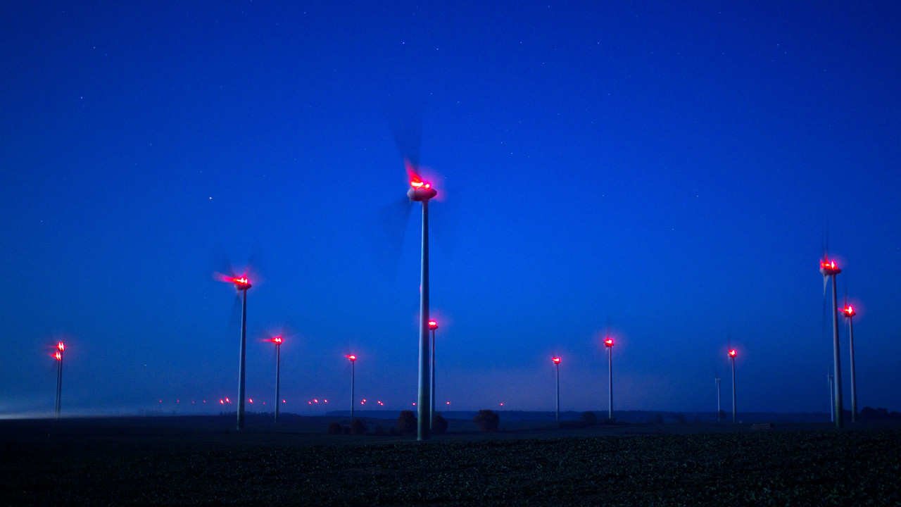 Beleuchtete Windräder drehen sich in der Nacht