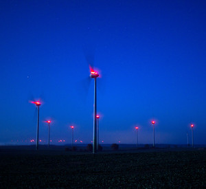 Beleuchtete Windräder drehen sich in der Nacht