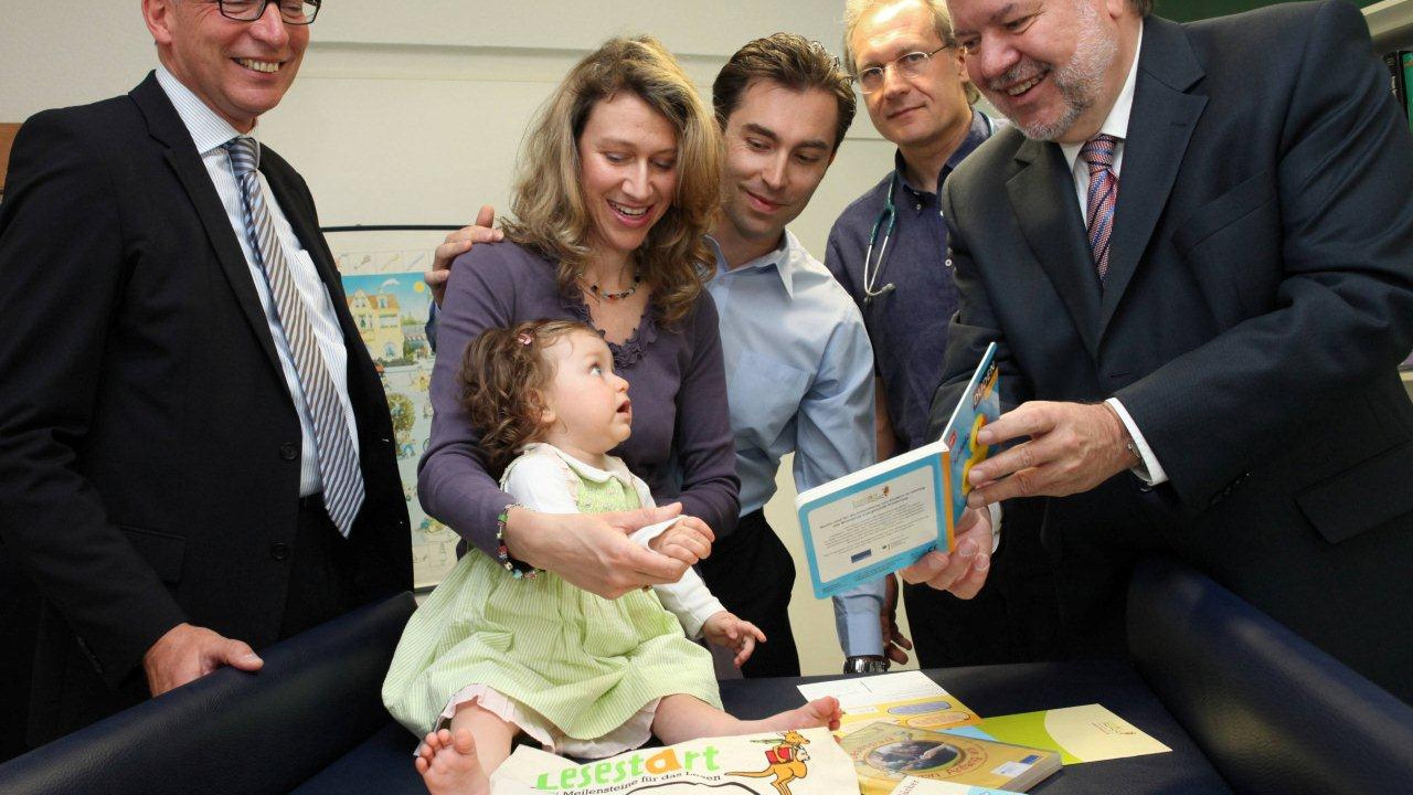 v.l. Hauptgeschäftsführer Jörg Maas, die kleine Carmen-Maria mit Eltern, Dr. med. Pirmin Habermehl, Mininsterpräsident Kurt Beck bei der Überreichung des Lesestart-Sets; Bild: Alexander Sell / © Staatskanzlei