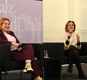 Ministerpräsidentin Malu Dreyer und Politikwissenschaftlerin Natascha Strobl mit Mikrofonen auf Sesseln sitzend.