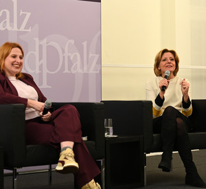 Ministerpräsidentin Malu Dreyer und Politikwissenschaftlerin Natascha Strobl mit Mikrofonen auf Sesseln sitzend.