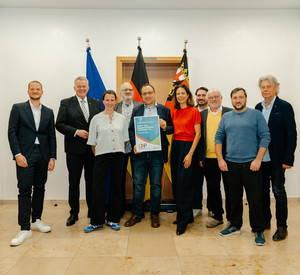 Gruppenfoto mit 10 Personen: Preisträger, Ministerpräsident, Vorsitzende der Stiftung. Alle blicken fröhlich, einer der Preisträger hält die Auszeichnung nach vorne.