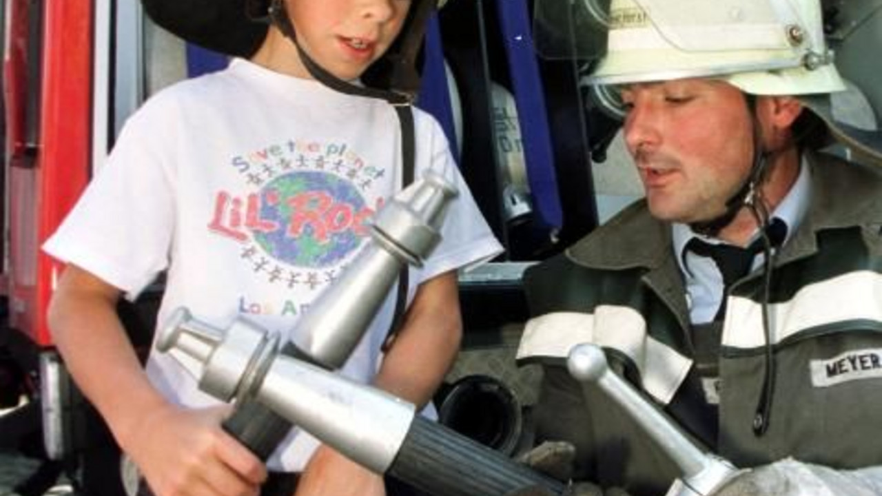 Feuerwehrmann erklärt einem Jungen Geräte; Bild: dpa
