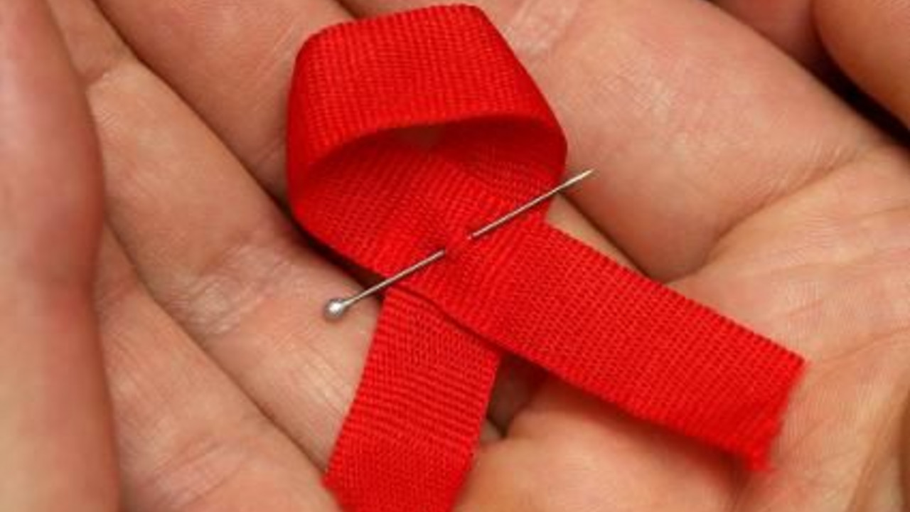 Frauenhände halten eine Aidsschleife; Bild: dpa