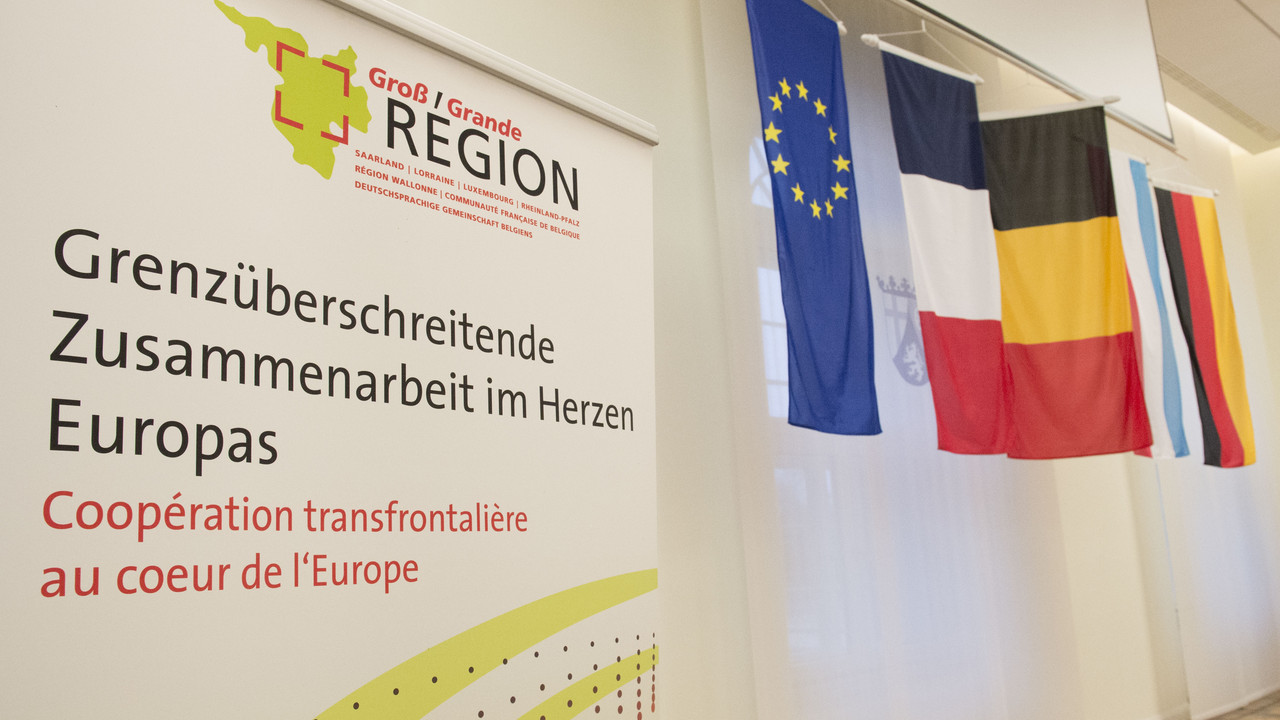 Das Plakat der Großregion neben den Flaggen von EU, Frankreich, Belgien, Luxemburg und Deutschland.