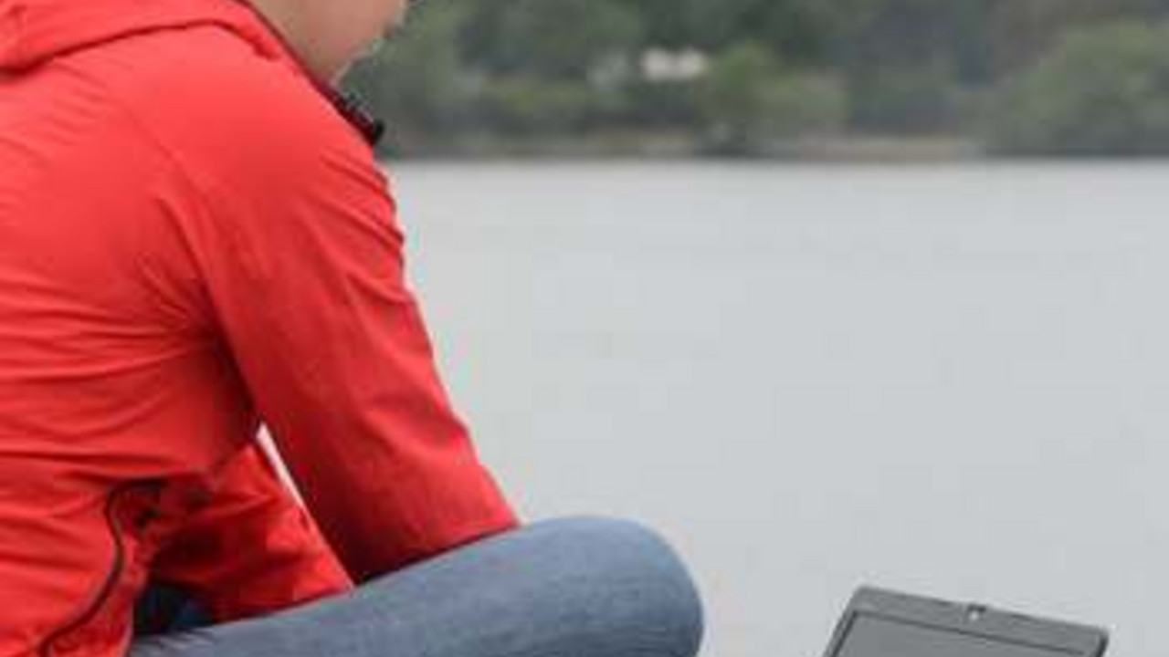 Frau mit Laptop am See; Bild: dpa