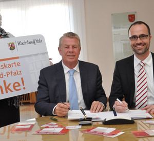 Oberbürgermeister der Stadt Worms, Michael Kissel, und der Chef der Staatskanzlei, Staatssekretär Clemens Hoch, unterzeichnen die Kooperationsvereinbarung.