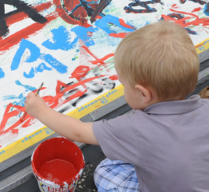 Junge malt mit roter Farbe; Bild: dpa