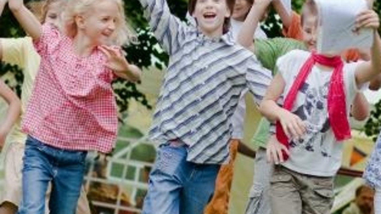 Kinder laufen mit Zeugnissen winkend über eine Wiese; Bild: dpa