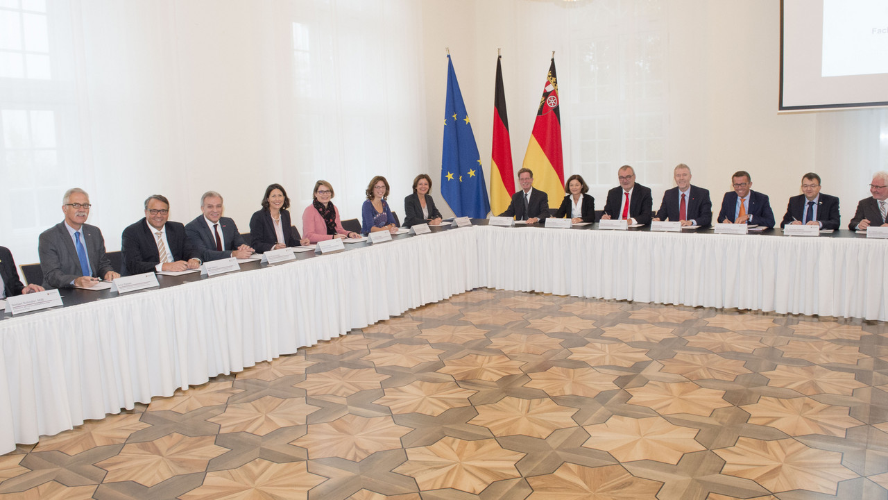 Ovaler Tisch der Ministerpräsidentin. Mit einer feierlichen Unterzeichnung besiegelt die Landesregierung zusammen mit den Partnerinnen und Partnern der Wirtschaft, der Gewerkschaften, der Kammern und der Bundesagentur für Arbeit ihre Zusammenarbeit.
