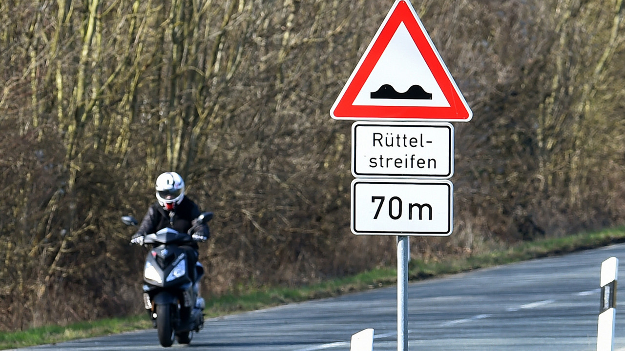 Motorradfahrer mit Hinweisschild