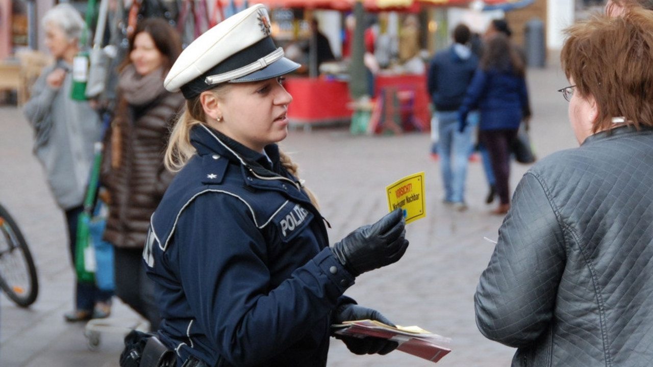 Polizeibeamtin übergibt Informationsmaterial