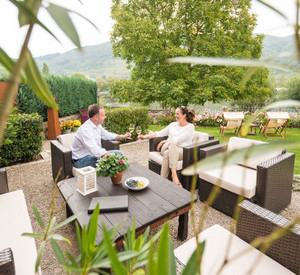 Ein Pärchen stößt auf einer Hotelterasse mit einem Glas Wein an.