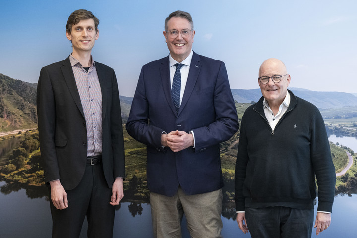 Gruppenbild von Daniel Kieslinger, Alexander Schweitzer und Albrecht Bähr vor einem Wandbild der Moselschleife.