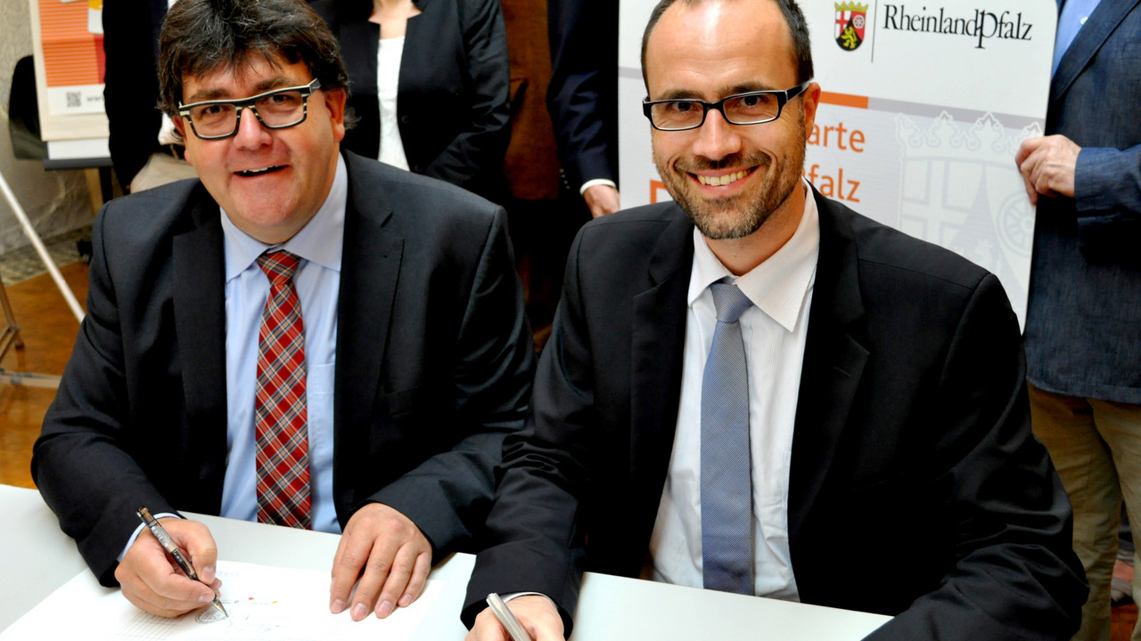 Der Chef der Staatskanzlei, Clemens Hoch, und der Bürgermeister der VG Nassau, Udo Rau, bei der Unterzeichnung der Kooperationsvereinbarung
