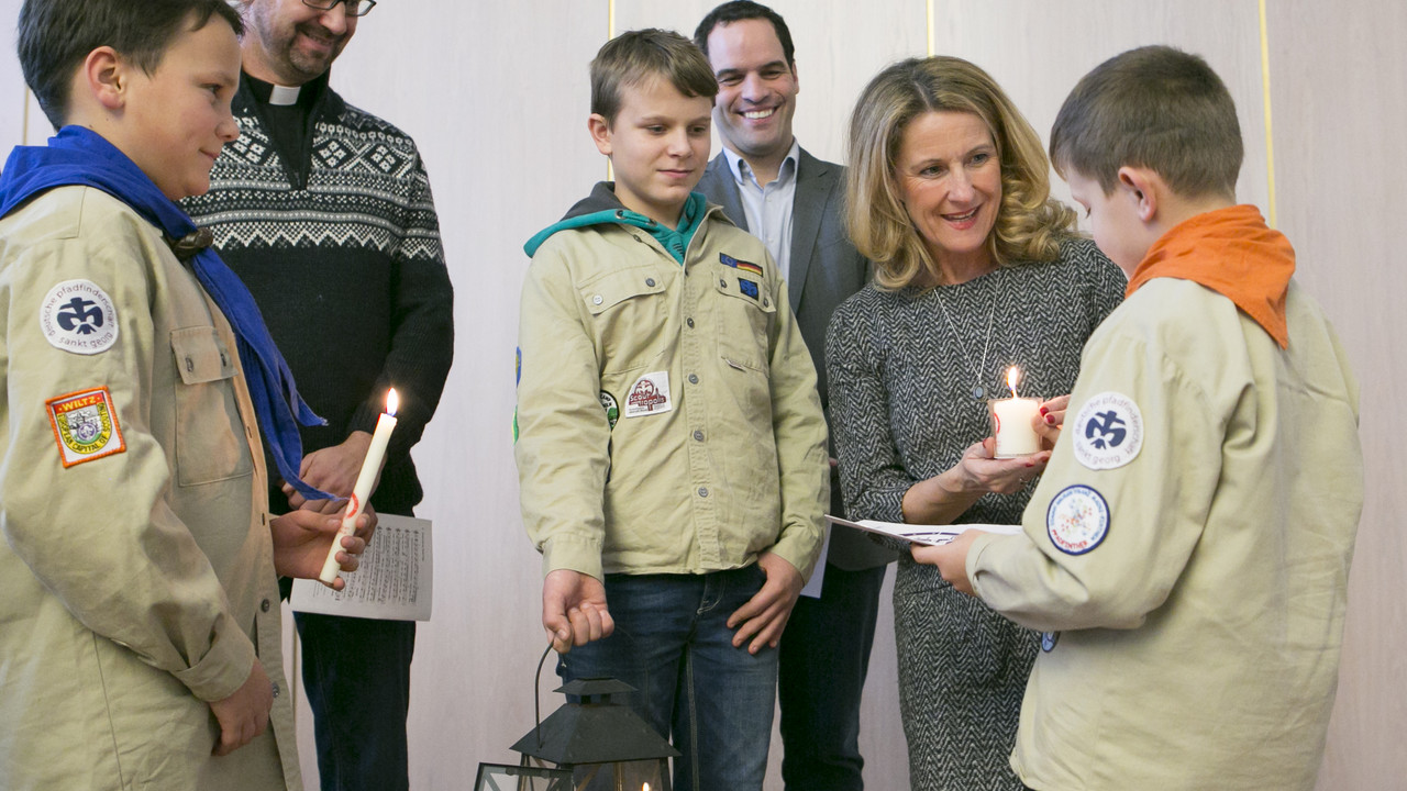 Pfadfinderinnen und Pfadfinder aus dem Bistum Mainz überreichen Staatssekretärin Heike Raab das Friedenslicht.