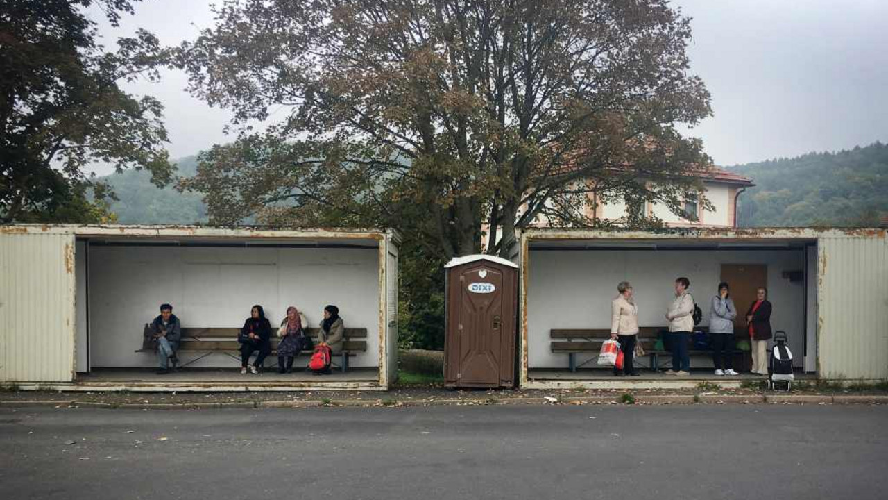 Foto von Klug: Einwohner in Thüringen warten neben Flüchtlingen auf Bus