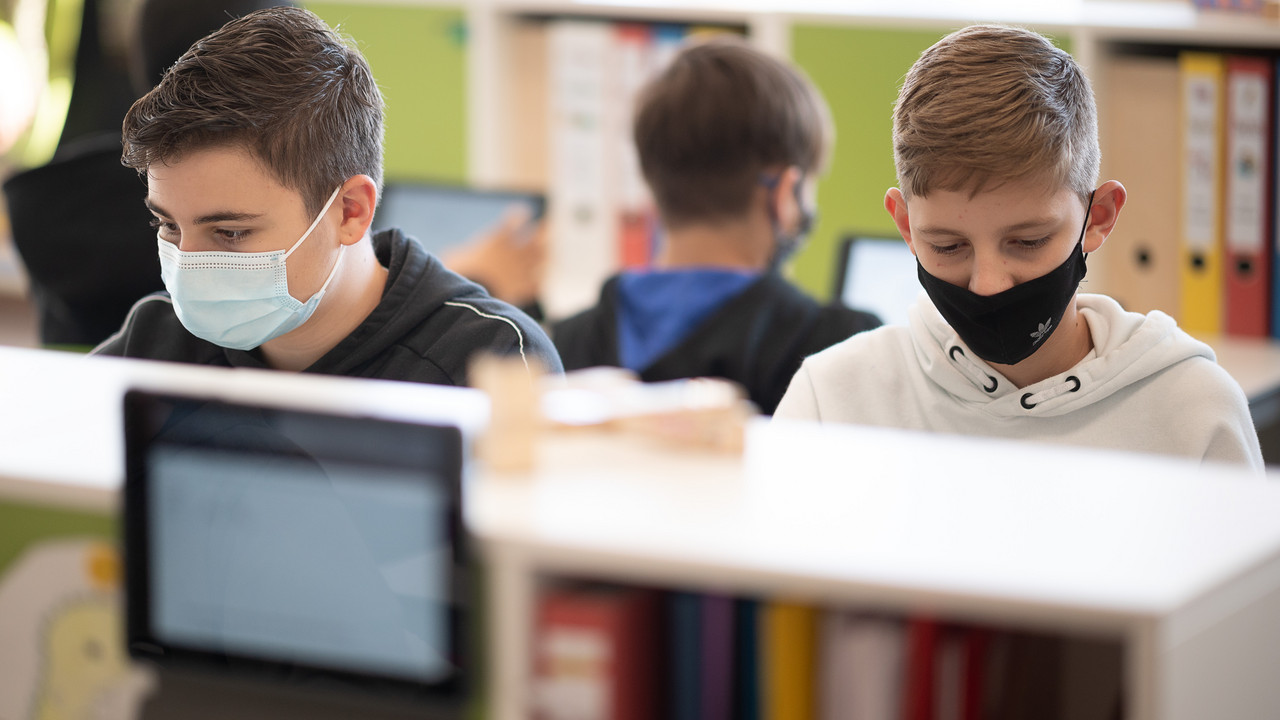 Schüler mit Mund- und Nasenschutz arbeiten in einer siebten Klasse einer Gemeinschaftsschule mit Tablets.