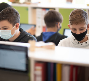 Schüler mit Mund- und Nasenschutz arbeiten in einer siebten Klasse einer Gemeinschaftsschule mit Tablets.