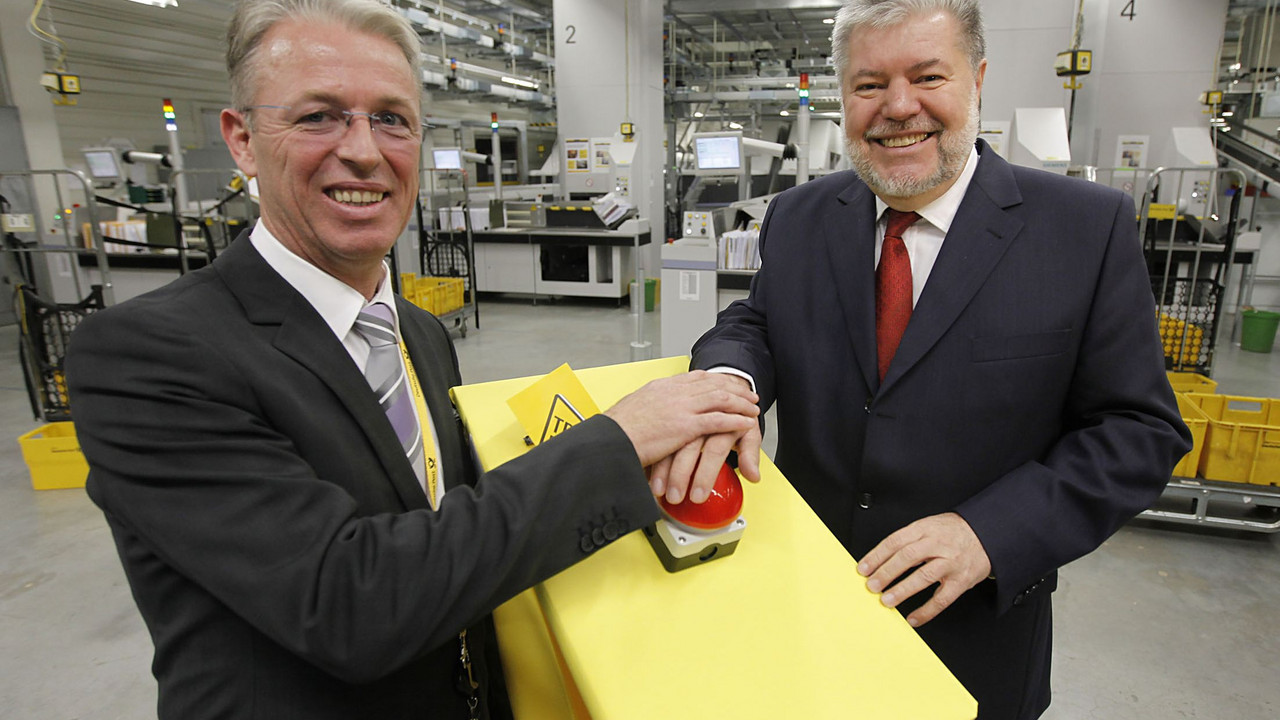 Der Chef der Briefniederlassung Mainz, Jörg Bahls, und Ministerpräsident Kurt Beck nehmen die neue Großbriefverteilmaschine in Betrieb. Bild: Georg / Pressestelle Deutsche Post