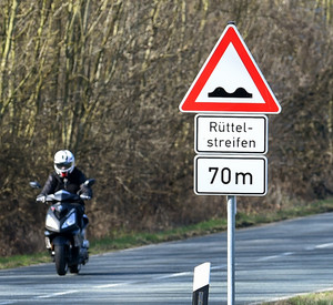 Motorradfahrer mit Hinweisschild