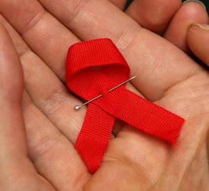 Frauenhände halten eine Aidsschleife; Bild: dpa