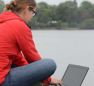 Frau mit Laptop am See; Bild: dpa