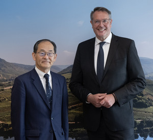 Der japanischen Botschafter Hidenao Yanagi steht neben Ministerpräsident Alexander Schweitzer. Im Hintergrund ein Wandbild der Moselschleife.