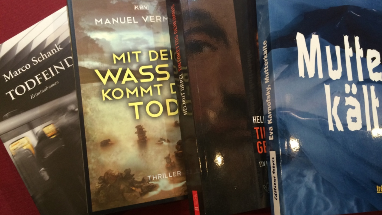 Vier Bücher liegen auf einem roten Untergrund