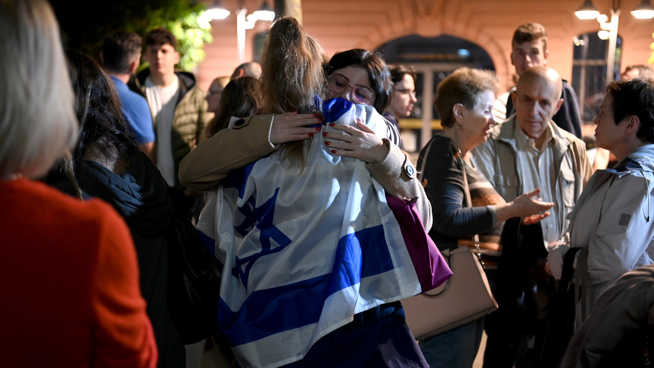Demonstrantin umarmt andere Demonstrantin, welche Israelflagge über den Rücken gehängt trägt.