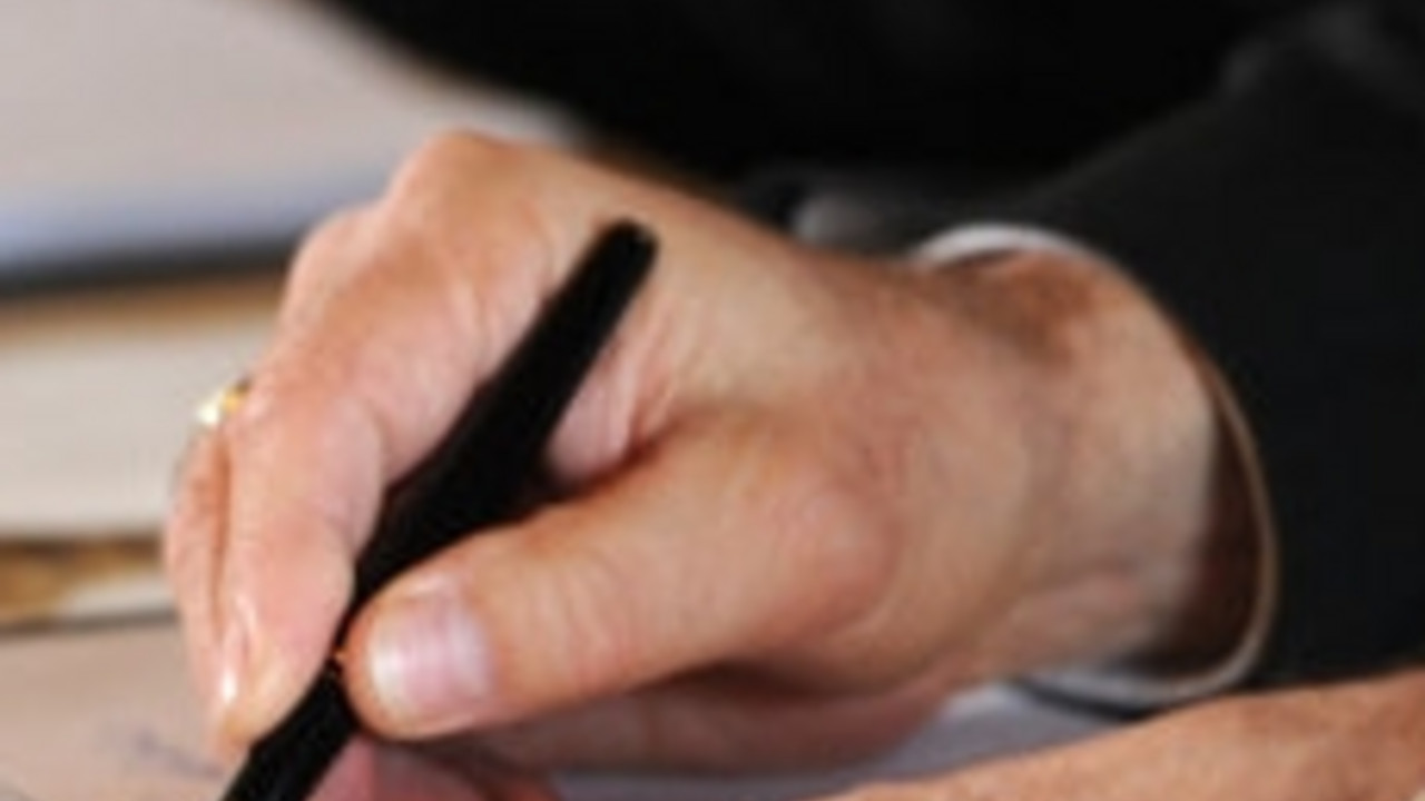 Hand beim Unterschreiben; Bild: dpa