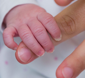 Baby greift nach der Hand eines Erwachsenen; Bild: dpa